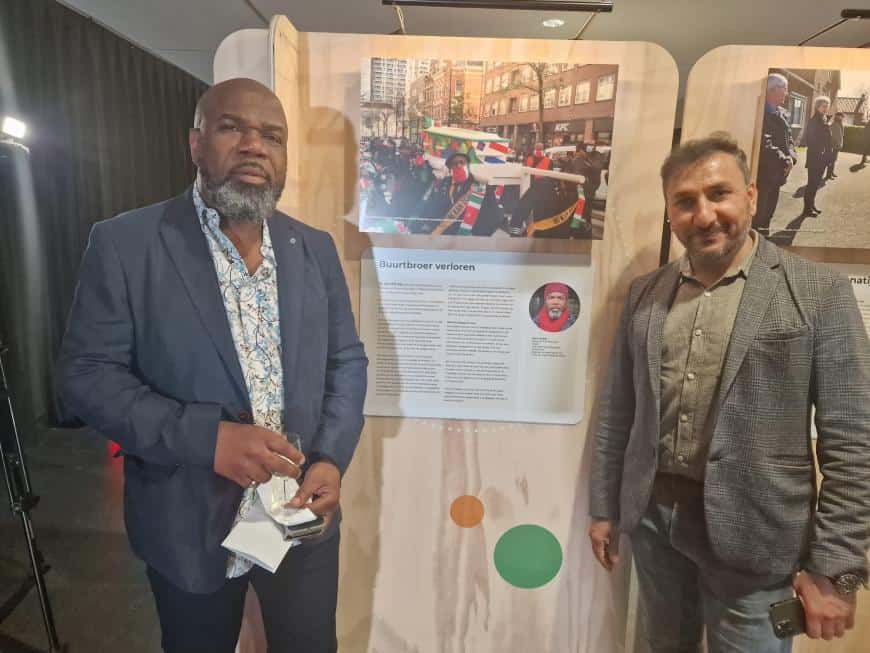 Guno Zwakke links, met collega ondernemer van de West Kruiskade, bij het artikel en foto van het afscheid van Fred Fitzjames